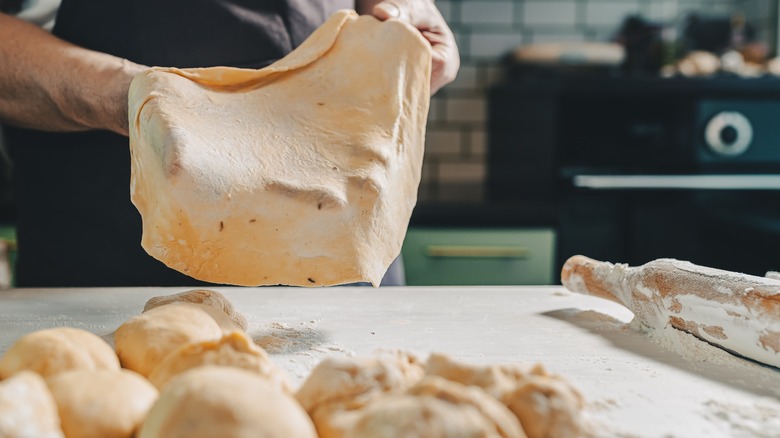 Baker stretching dough