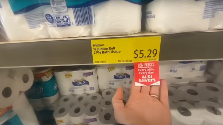 Hand pointing to price label for Aldi toilet roll