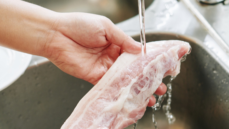 person rinsing piece of bacon