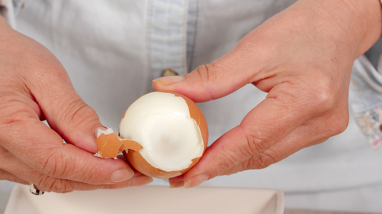 person peeling boiled egg