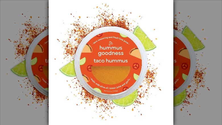 Hummus container surrounded by spices and lime