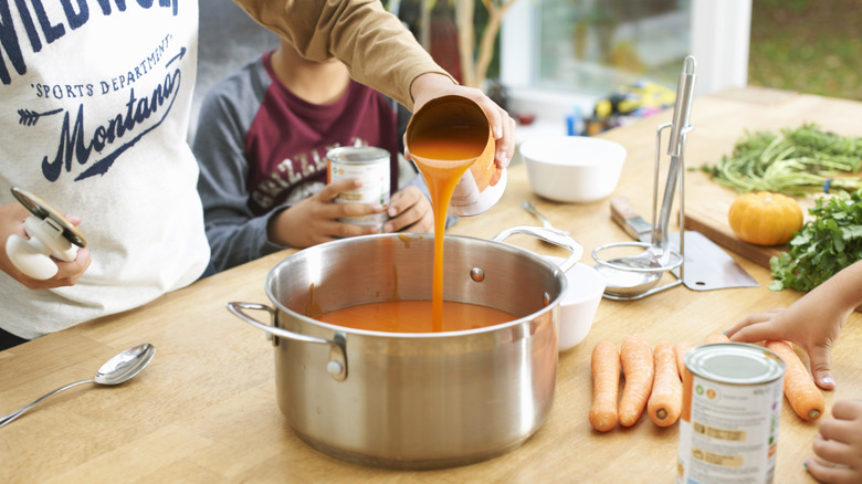 pouring canned soup into pot