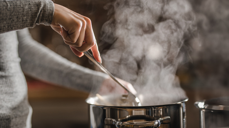 person stirring pot with ladel