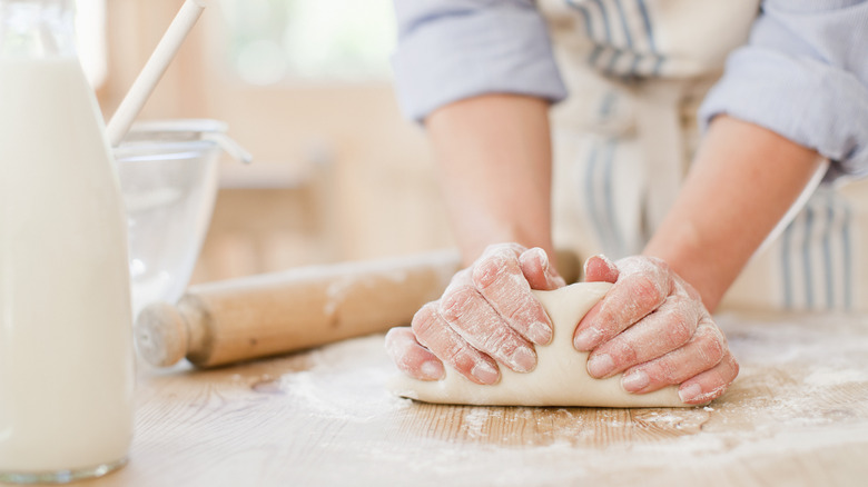 person kneading bread on counter