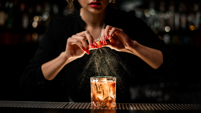 bartender garnishing cocktail with citrus