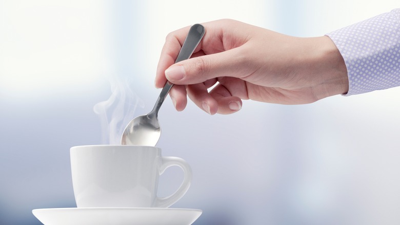 Person stirring hot coffee