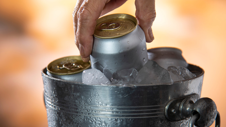 Person pulling a can from a bucket of ice
