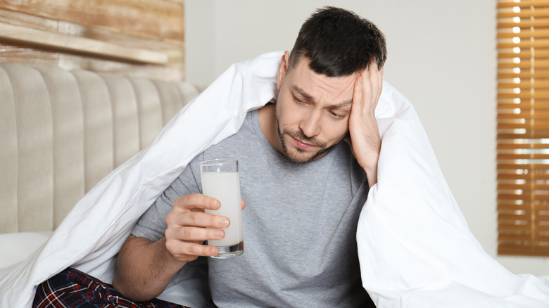 Man sitting in bed with medicine for hangover