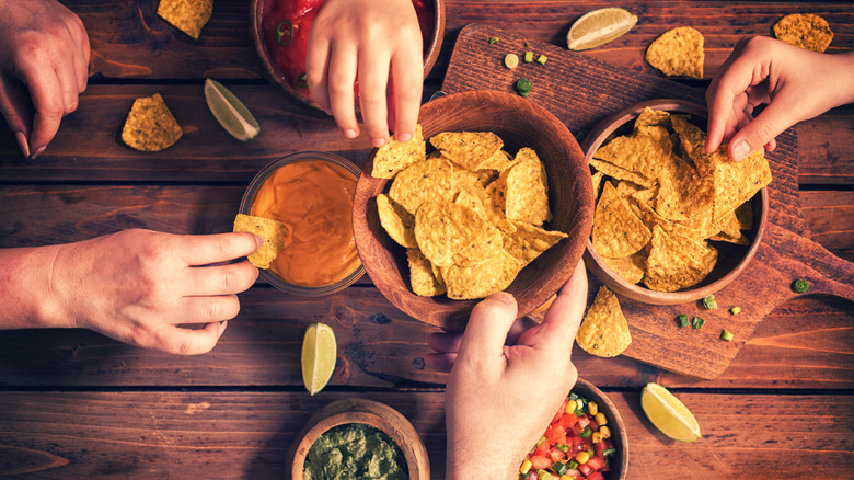 hands sharing chips and dip