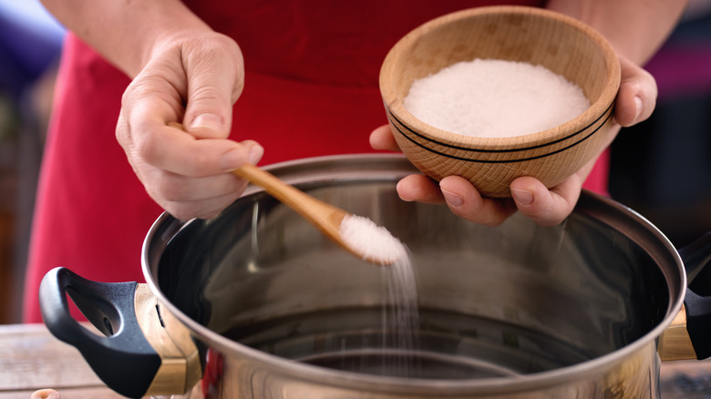 Person adding salt to water