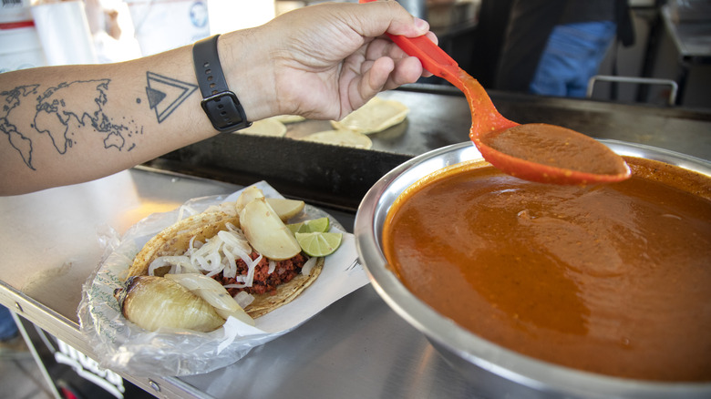 person adding salsa to taco