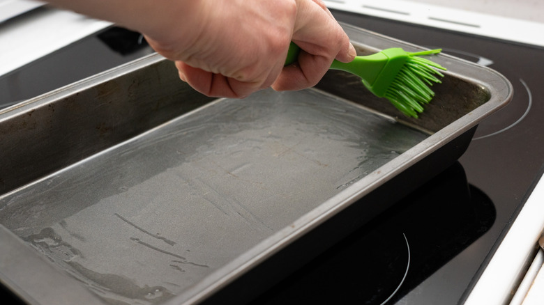 person greasing baking sheet