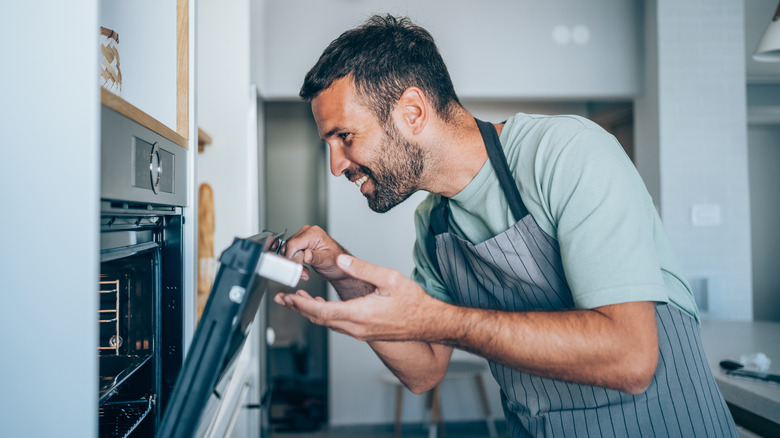 man peeking in oven