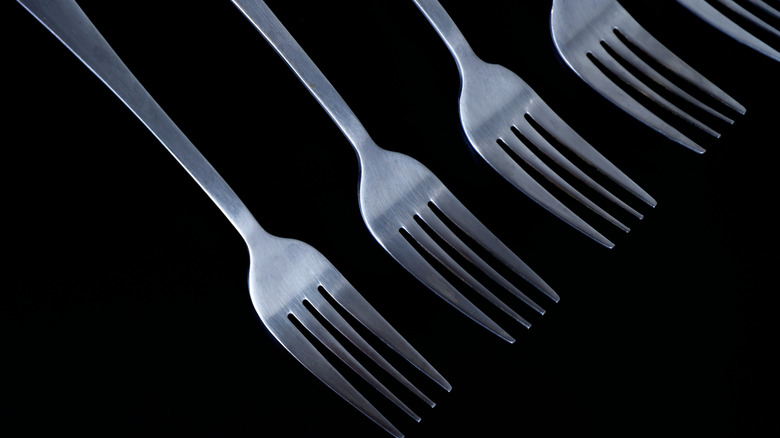 Stainless steel forks on black background.