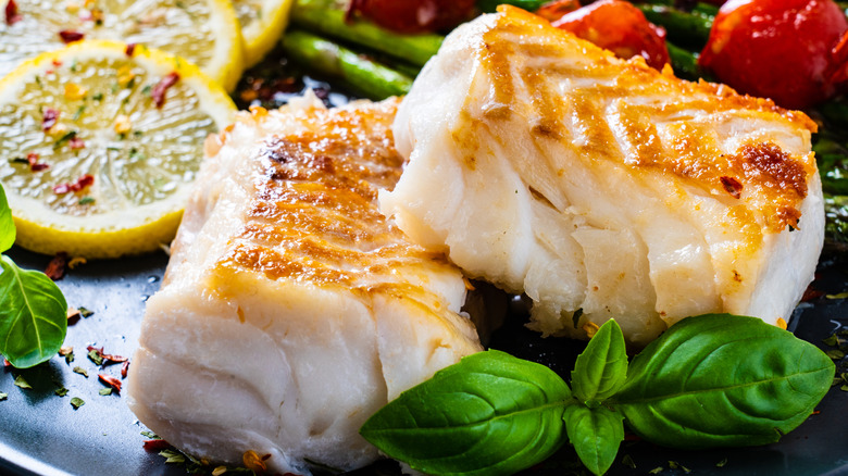 Seared cod fillets with fresh herbs and vegetables.