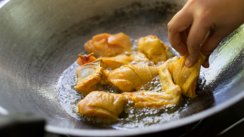 Person putting chicken in wok