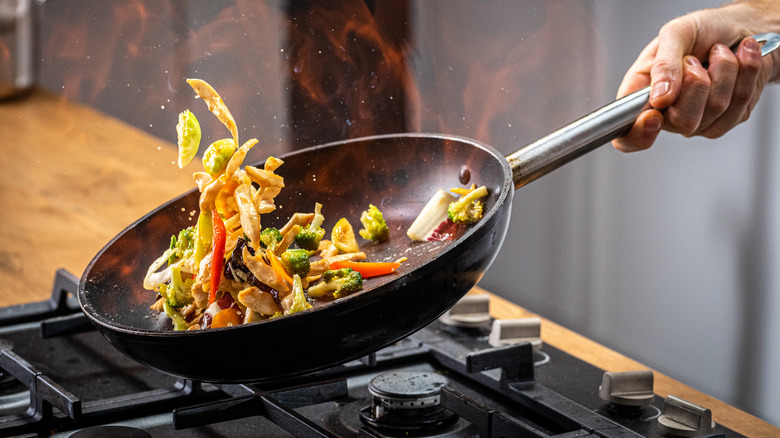 Person flipping food in wok