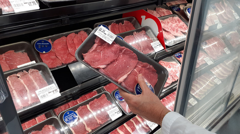 Hand holding packaged steak