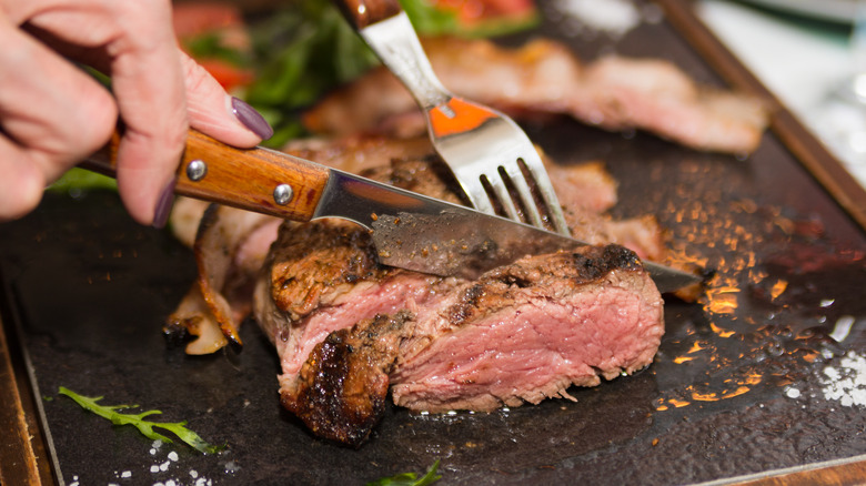 Knife and fork cutting steak