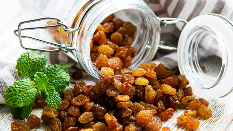 Golden raisins near glass jar