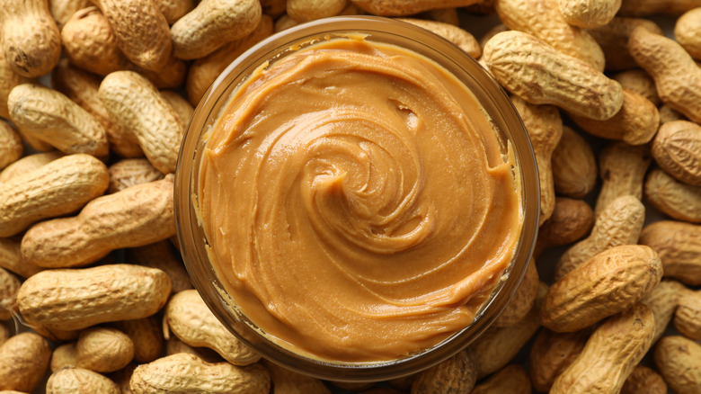 Peanut butter in jar with peanuts