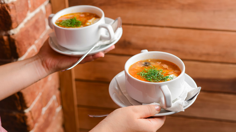 waiter serving two cups of soup