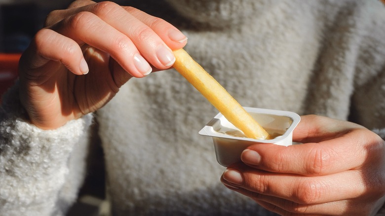 Woman dunking french fry into dipping sauce