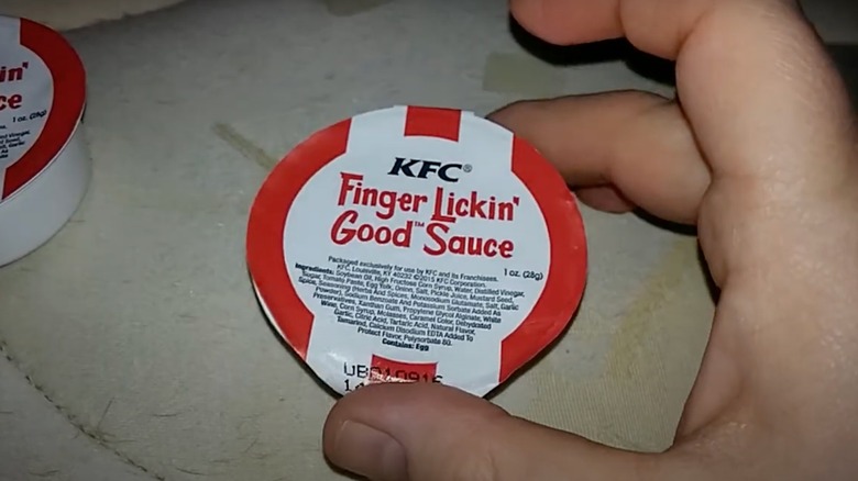 Person holding pot of KFC Finger Lickin' Good Sauce