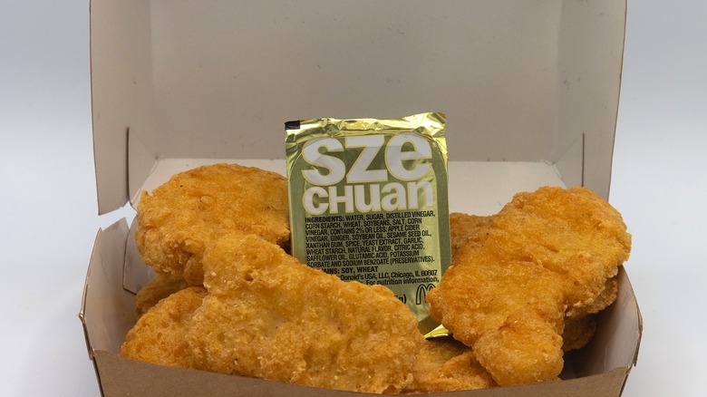 Carton of chicken nuggets with carton of Szechuan Sauce in the middle