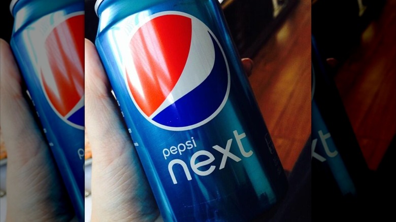 Hand holding can of Pepsi Next