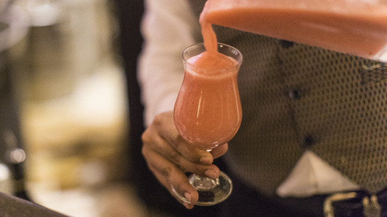 Bartender pouring blended drink into glass