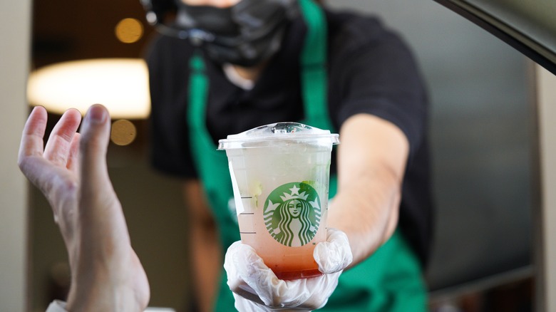 Person's hand passing Starbucks drink