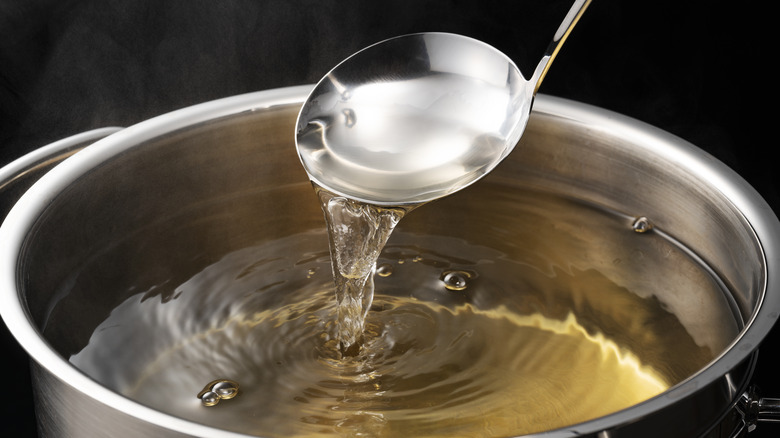 Ladle pouring dashi stock into full pot