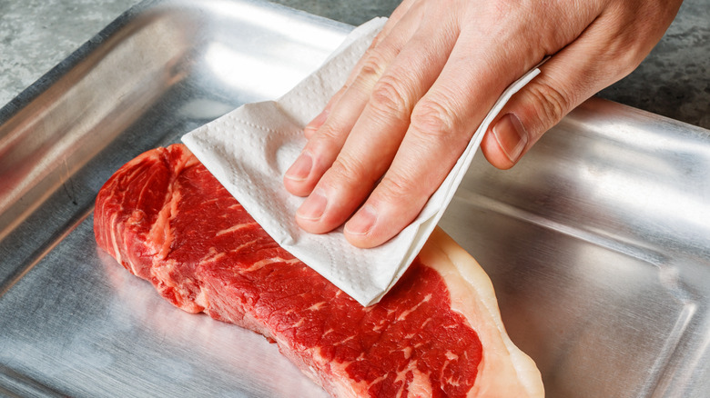 person drying piece of steak