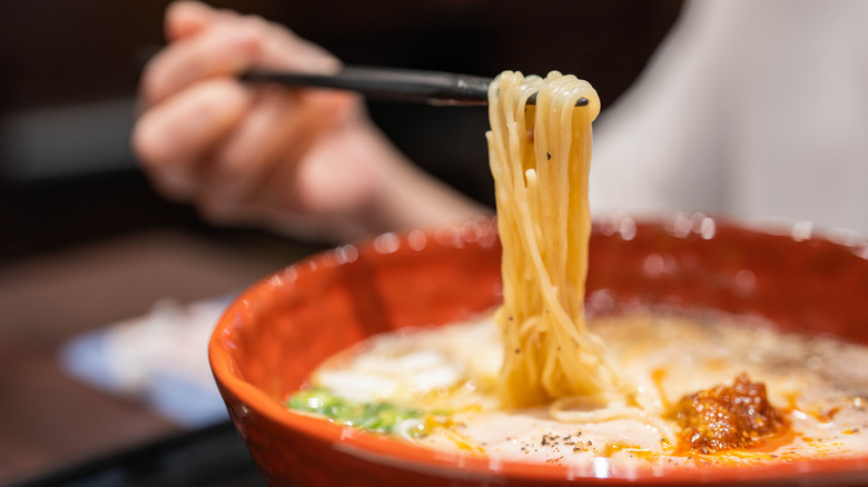 Bowl of ramen, with a bundle of noodles being lifted up with chopsticks