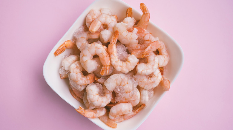 Frozen raw shrimp on pink background