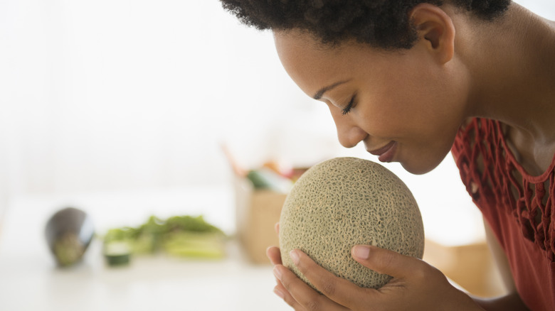 woman smelling a cantaloupe