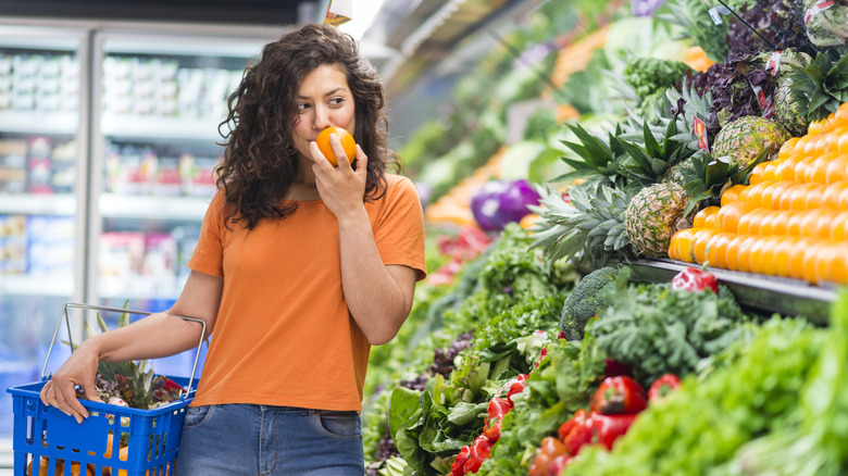 woman smelling vegetable in store