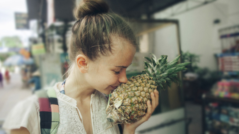 woman smelling pineapple