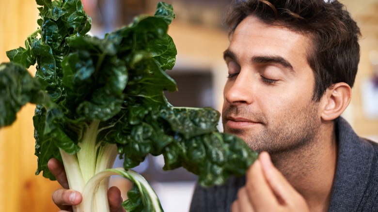 man smelling spinach