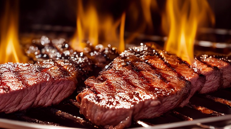 Steaks grilling over flame