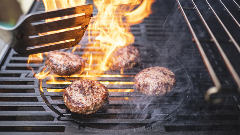 hamburgers cooking on flaming grill