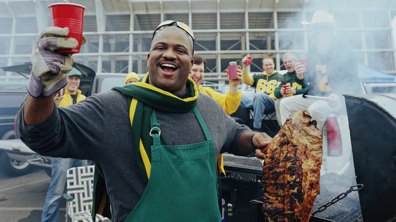 man grilling meat at tailgate