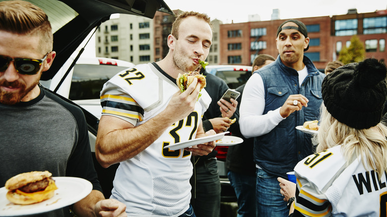 man eating burger at tailgate