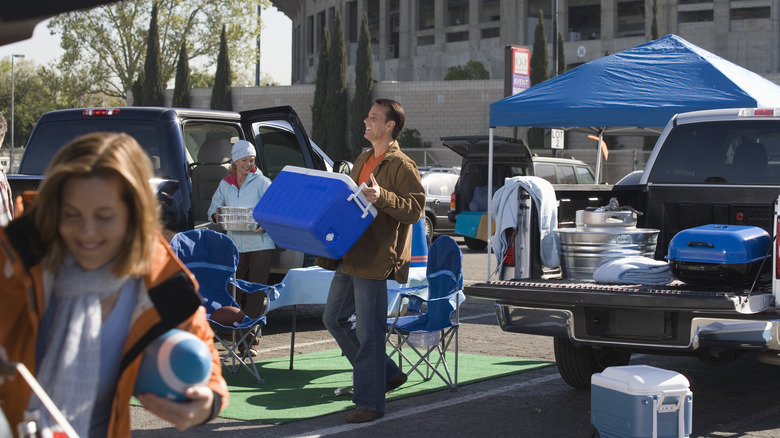 man carrying cooler at tailgate