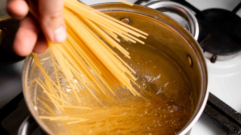 spaghetti being placed in pan