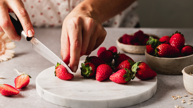 Person chopping fresh strawberries