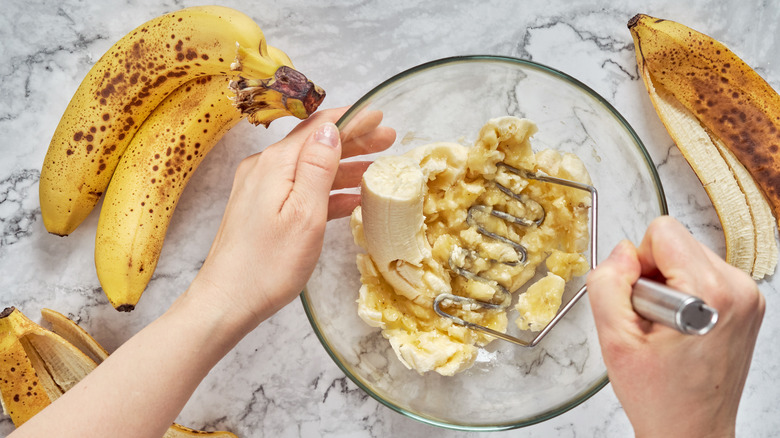 Person mashing bananas in bowl