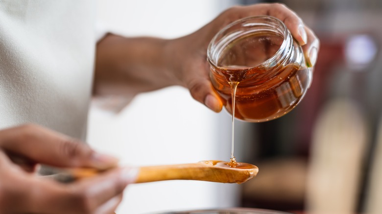 woman pouring honey onto spoon