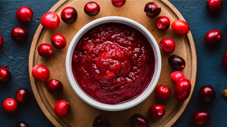 Bowl of cranberry sauce, surrounded by fresh cranberries